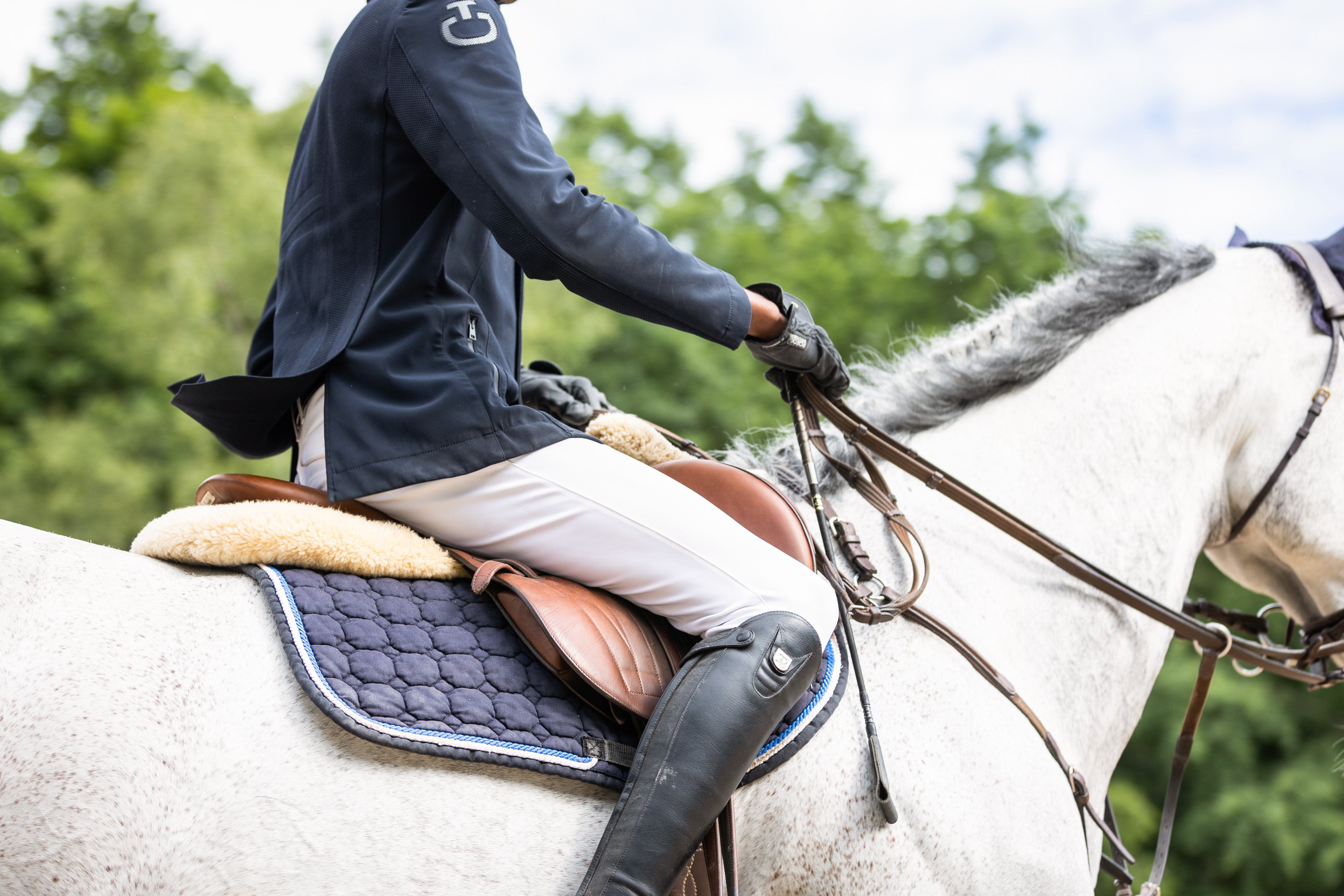 Detailfoto von einem Springreiter auf einem Turnier, Reiter von der Schulter bis zum Knöchel sichtbar, oberer Teil vom Pferd sichtbar, Kopf und Kruppe nicht sichtbar