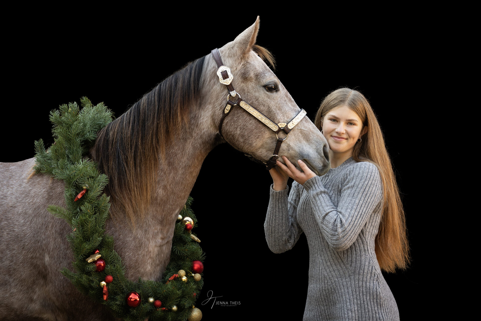 Mädchen kuschelt mit ihrem jungen Quarter Horse vor schwarzem Hintergrund, Weihnachtsdekoration