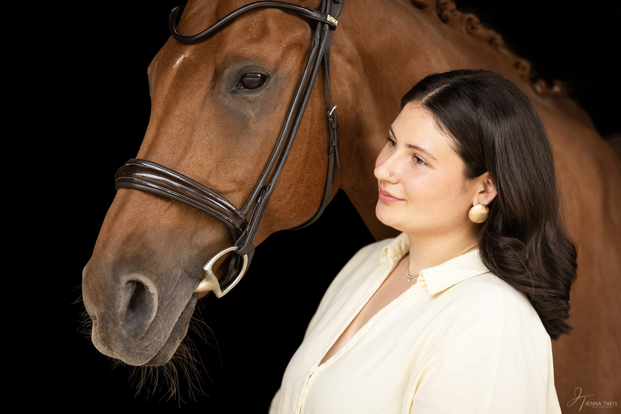 Elegantes Portrait von einer Frau und ihrem Pferd vor schwarzem Hintergrund